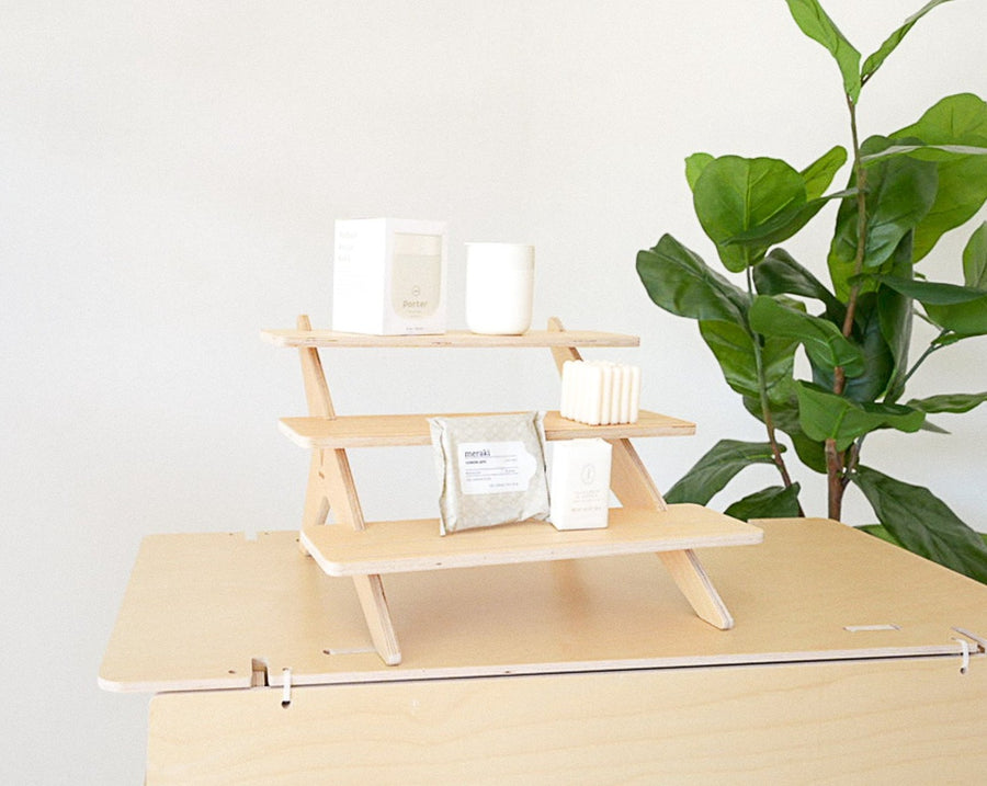 Flat Pack Tiered Wood Shelving Unit in Retail Store: A minimalist tiered wood shelving unit from Vertical Ledge, showcasing various retail items in a modern store setting.